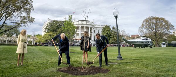 n this April 23, 2018, file photo, first lady Melania Trump, second from right, and Brigitte Macron, left, watch as President Donald Trump and French President Emmanuel Macron participate in a tree planting ceremony on the South Lawn of the White House in Washington - Sputnik International