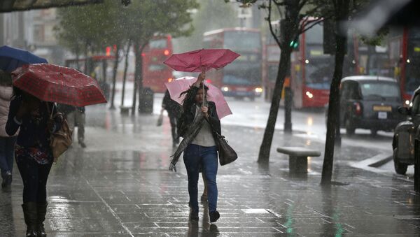 A woman's umbrella blown inside-out as she walks through a heavy rain shower on Oxford Street in London (File) - Sputnik International
