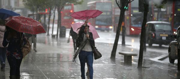A woman's umbrella blown inside-out as she walks through a heavy rain shower on Oxford Street in London (File) - Sputnik International