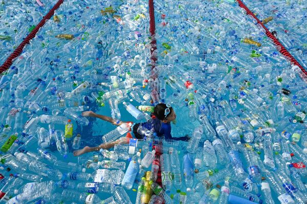 A child swims in a pool filled with plastic bottles during an awareness campaign to mark the World Oceans Day in Bangkok on June 8, 2019. - Sputnik International