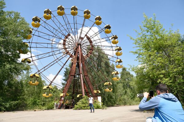 Visitors take pictures at an amusement park in the abandoned city of Pripyat, near the Chernobyl Nuclear Power Plant in Ukraine.  - Sputnik International