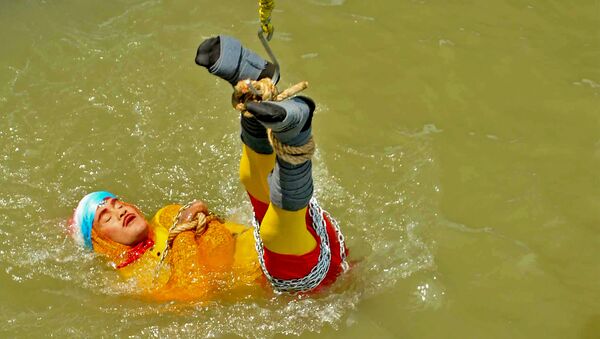 Chanchal Lahiri, known by his stage name Jadugar Mandrake, is lowered into the Ganges river, while tied up with steel chains and ropes, in Kolkata. - Sputnik International