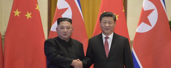 In this Tuesday, Jan. 8, 2019, photo released by China's Xinhua News Agency, North Korean leader Kim Jong Un, left, and Chinese President Xi Jinping shake hands as they pose for a photo before talks at the Great Hall of the People in Beijing - Sputnik International
