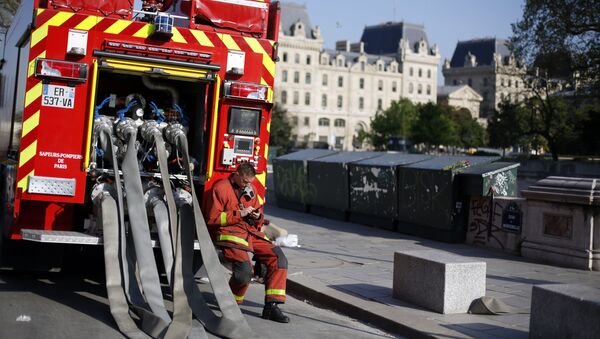 A firefighter checks his phone as he rests nearby the Notre Dame cathedral, in Paris, Friday, April 19, 2019.  - Sputnik International