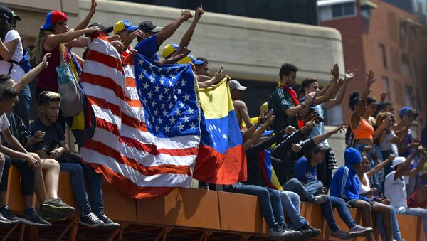 Anti-government protesters hold the US national flag next to a Venezuelan national flag during the commemoration of May Day in Caracas, on May 1, 2019 after a day of violent clashes on the streets of the capital spurred by Venezuela's opposition leader Juan Guaido's call on the military to rise up against President Nicolas Maduro - Sputnik International