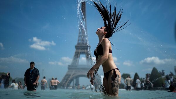 A woman plays the water as she cool herself down in the fountain of the Trocadero esplanade in Paris on June 25, 2019 with the Eiffel Tower on the background - Sputnik International