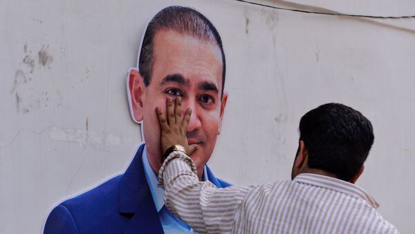 An Indian supporters of the Congress Party keeps his hand on the face of a cut out of billionaire jeweller Nirav Modi during a protest in New Delhi on February 16, 2018 - Sputnik International