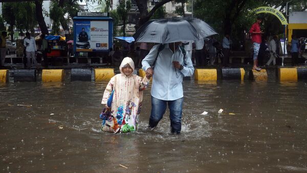 A man and his daughter wade through a waterlogged street during heavy rains in Mumbai, India, June 28, 2019 - Sputnik International