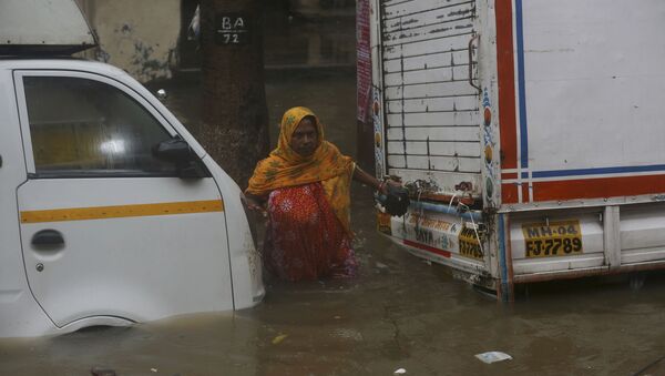 A woman tries to cross through a waterlogged street during monsoon rains in Mumbai - Sputnik International
