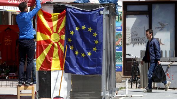 A street vendor fixes a North Macedonia flag next to an EU flag in a street in Skopje - Sputnik International