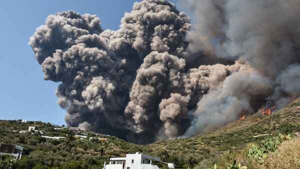 Smoke billows and flames propaqate accross the hillside neqr houses after the Stromboli volcano erupted on July 3, 2019 on the Stromboli island, north of Sicily - Sputnik International