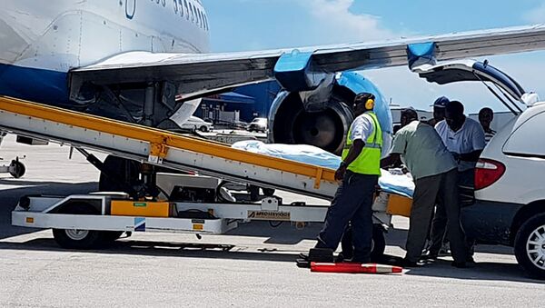In this handout photo released by the Bahamas ZNS Network, employees oversee the arrival of the bodies of four women and three men, including billionaire coal entrepreneur Chris Cline and his daughter, at the airport in Nassau, Bahamas - Sputnik International