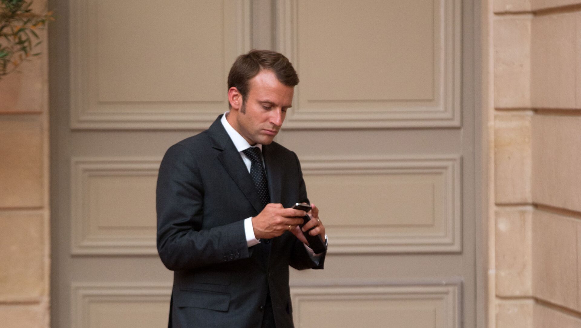Emmanuel Macron, looks at his phone. - Sputnik International, 1920, 20.07.2021