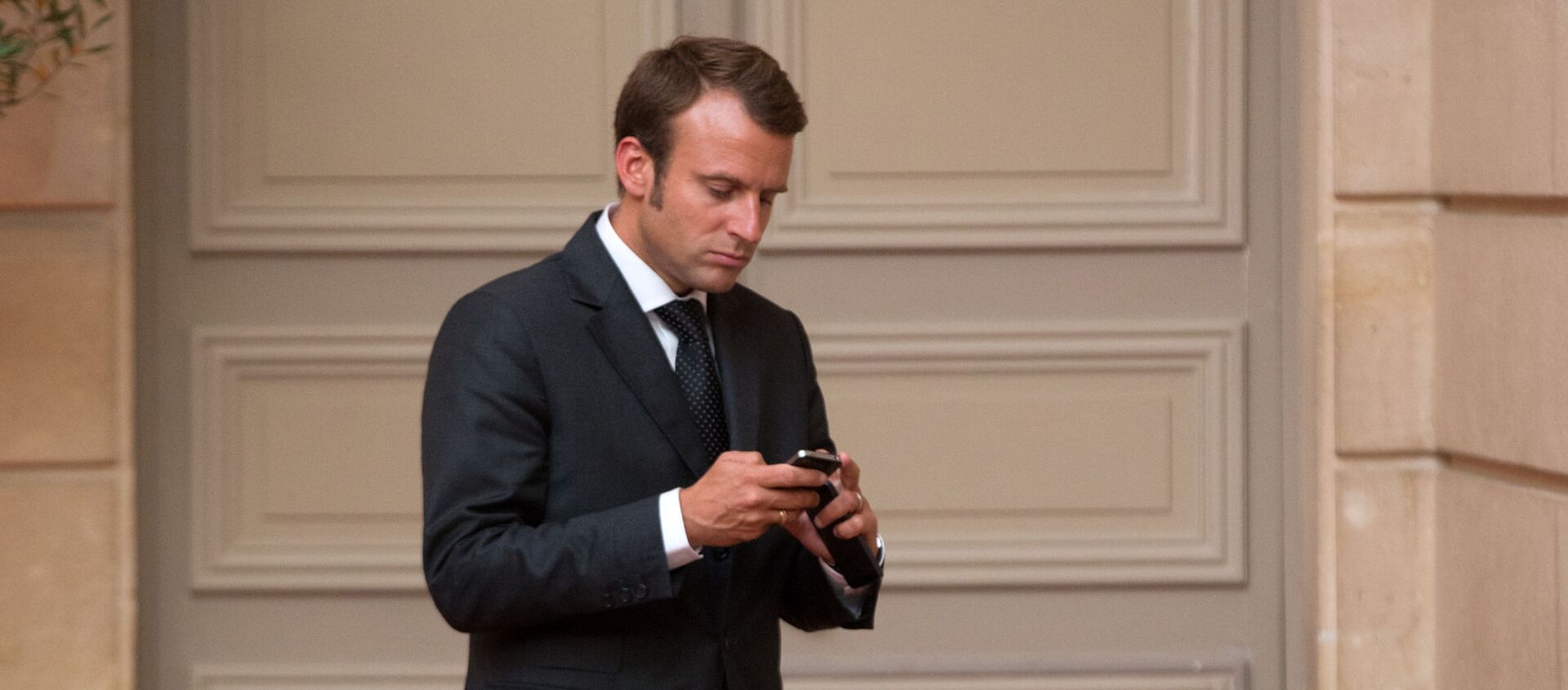 Emmanuel Macron, looks at his phone. - Sputnik International, 1920, 20.07.2021