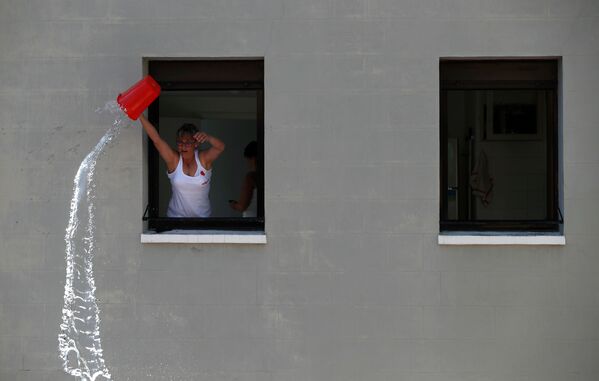 Женщина льет воду на участников фестиваля Сан-Ферми в Памплоне, Испания - Sputnik International