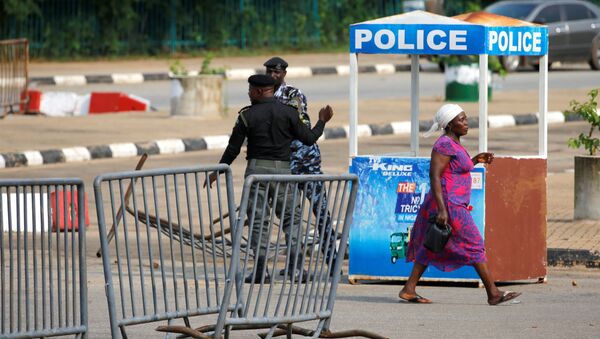A woman walks past police officers outside the National Assembly in Abuja - Sputnik International