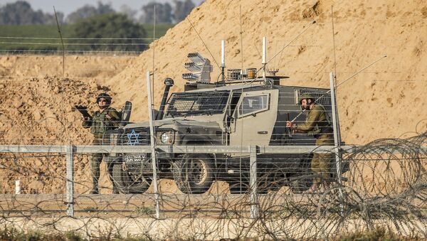 Israeli soldiers are seen next to a military vehicle across the barbed-wire border fence with the Gaza Strip - Sputnik International