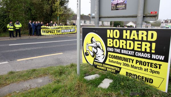 Protesters against Brexit and the possible imposition of any hard border between Northern Ireland and Ireland  gather with a banner at the border (marked where the tarmac changes and the lines change between white and yellow) between Derry (Londonderry) in Northern Ireland and County Donegal in the Republic of Ireland near the Irish village of Bridge End on April 18, 2019 - Sputnik International