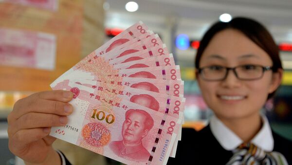 A bank employee shows new 100-yuan banknotes in Handan, north China's Hebei province on November 12, 2015 - Sputnik International
