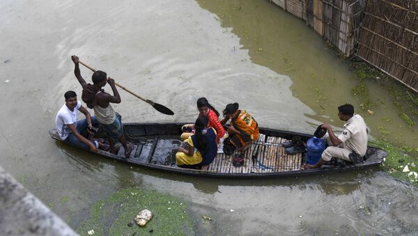 An Indian policeman travels with residents on a wooden boat to cross a flooded locality near the Ahiyapur police station at Muzaffarpur district in the Indian state of Bihar on July 18, 2019 - Sputnik International