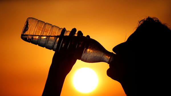 A woman drinks water during sunset, as a heatwave - Sputnik International