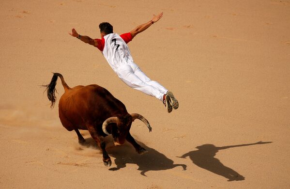 A recortador jumps over a bull during a contest in a bullring at the San Fermín festival in Pamplona, Spain - Sputnik International