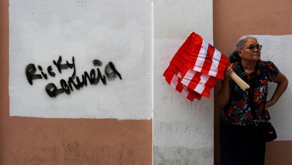 A woman sells Puerto Rican flags next to a graffiti that reads Ricky resign during the seventh day of protest calling for the resignation of Governor Ricardo Rossello in San Juan, Puerto Rico July 19, 2019. - Sputnik International