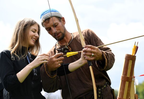 A participant shows a lady how to shoot a bow and arrow. - Sputnik International