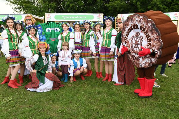 Women and children dressed in costumes stand near a promotion board representing Russia's Tula region. - Sputnik International