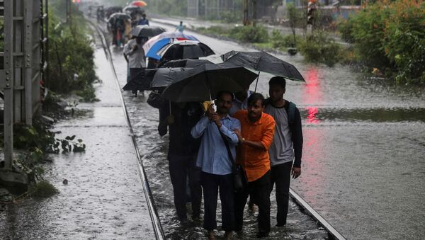 Commuters walk on waterlogged railway tracks after getting off a stalled train during heavy monsoon rains in Mumbai, India, July 2, 2019 - Sputnik International