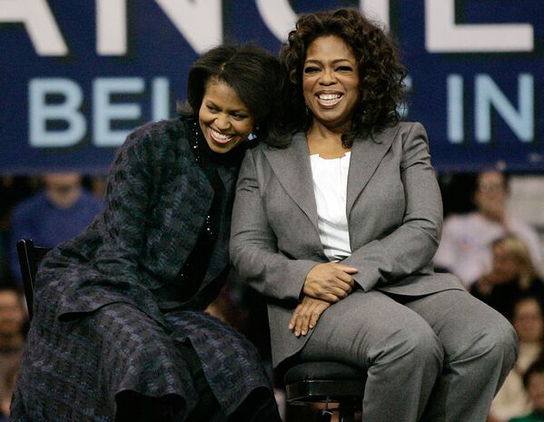 Michelle Obama, wife of then Democratic presidential hopeful Sen. Barack Obama, and TV host Oprah Winfrey sit together during a rally in Manchester on 9 Dec, 2007. - Sputnik International