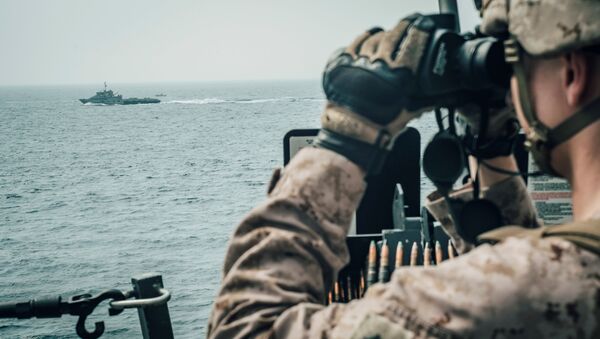 A U.S. Marine observes an Iranian fast attack craft from USS John P. Murtha during a Strait of Hormuz transit, Arabian Sea off Oman - Sputnik International