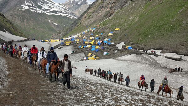 Hindu pilgrims treck through mountains to reach the Amarnath cave shrine where they worship an ice stalagmite that Hindus believe to be the symbol of Lord Shiva, at Sangam Top in the Kashmir region, July 6, 2019 - Sputnik International