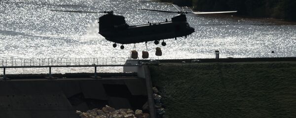 An RAF Chinook helicopter drops aggregate to help shore up a reservoir at risk of collapse, threatening to engulf the town of Whaley Bridge in the Peak District, England, Friday - Sputnik International