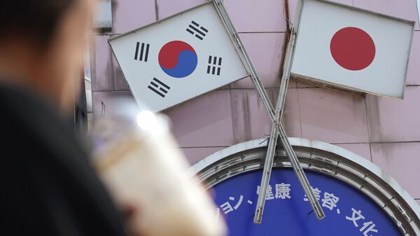 A woman walks past an advertisement featuring Japanese and South Korean flags at a shop in Shin Okubo area in Tokyo Friday, Aug. 2, 2019 - Sputnik International