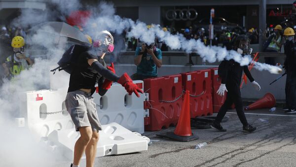 A protester throws back a tear gas canister in Hong Kong on Monday, Aug. 5, 2019. Droves of protesters filled public parks and squares in several Hong Kong districts on Monday in a general strike staged on a weekday to draw more attention to their demands that the semi-autonomous Chinese city's leader resign - Sputnik International