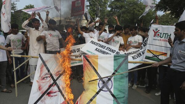 Pakistanis burn a poster of Indian Prime Minster Narendra Modi during a protest to express support and solidarity with Indian Kashmiri people in their peaceful struggle for their right to self-determination, in Lahore, Pakistan, Monday, Aug. 5, 2019. India's government has revoked disputed Kashmir's special status by a presidential order as thousands of troops patrolled and internet and phone services were suspended in the region where most people oppose Indian rule. (AP Photo/K.M. Chaudary) - Sputnik International