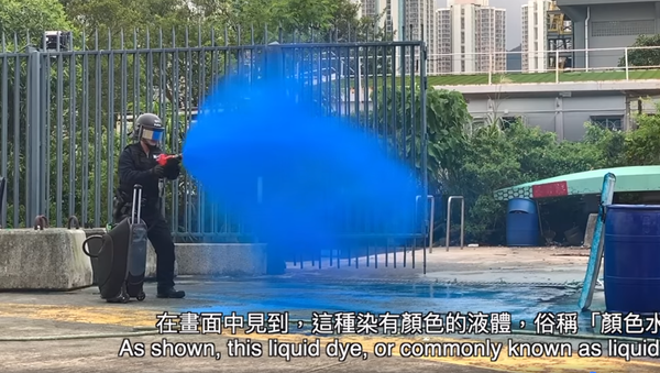 Hong Kong police official demonstrating the proper way to spray the new liquid dye used to tag and identify protesters  - Sputnik International