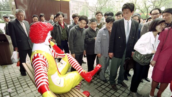 Passers-by keep their distance from Ronald McDonald as he sits outside the first McDonalds restaurant to be opened in Beijing on April 20, 1992. - Sputnik International