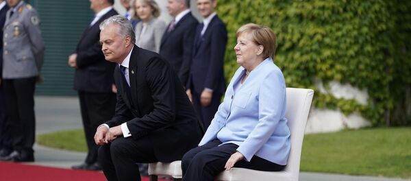 German Chancellor Angela Merkel and Lithuania's President Gitanas Nauseda sit down to listen to their national anthems during an official welcoming ceremony on August 14, 2019 at the Chancellery in Berlin - Sputnik International