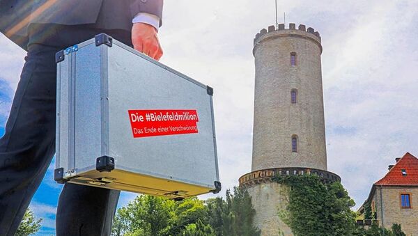 A man is holding a suitcase with 'the Bielefeld million' sticker against the backdrop of Sparrenburg Castle, a favourite tourist destination in Bielefeld. - Sputnik International