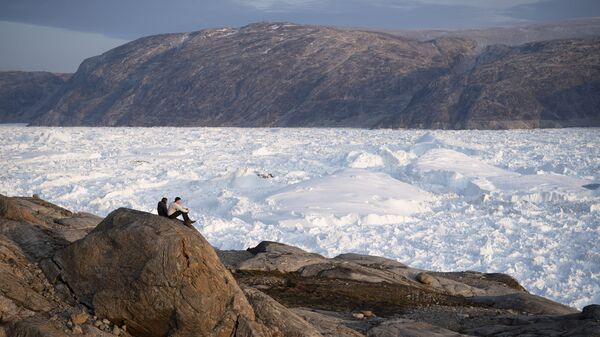 In this Aug. 16, 2019, photo, New York University student researchers sit on a rock overlooking the Helheim glacier in Greenland. - Sputnik International