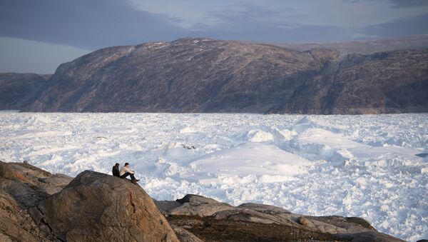 In this Aug. 16, 2019, photo, New York University student researchers sit on a rock overlooking the Helheim glacier in Greenland. - Sputnik International