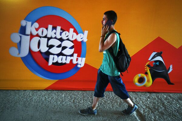 A young man passes by a logo of the international Koktebel Jazz Party festival. - Sputnik International