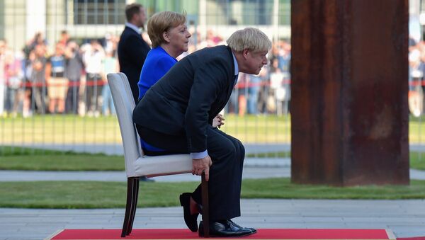 German Chancellor Angela Merkel and British Prime Minister Boris Johnson sit for the national anthems during a ceremony with military honours at the Chancellery on his first foreign visit since taking office on August 21, 2019 in Berlin - Sputnik International