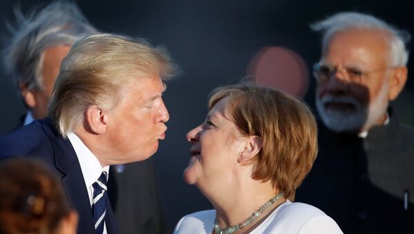 U.S. President Donald Trump and German Chancellor Angela Merkel lean in for a kiss during the family photo with invited guests at the G7 summit in Biarritz, France August 25, 2019.  - Sputnik International