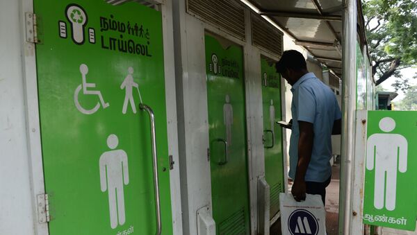 An Indian resident checks his phone as he waits to use a public toilet on a street in  Chennai on November 15, 2017 - Sputnik International