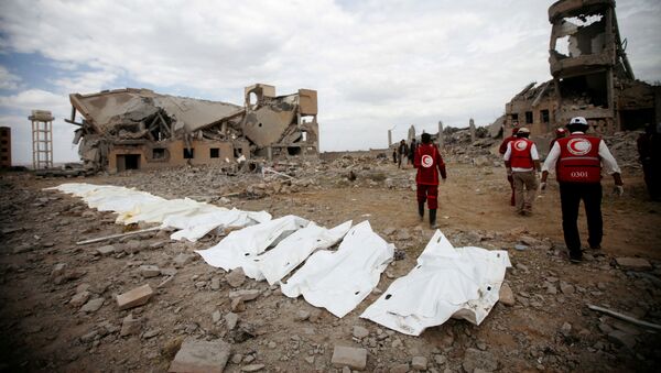 Red Crescent medics walk next to bags containing the bodies of victims of Saudi-led airstrikes on a Houthi detention centre in Dhamar - Sputnik International