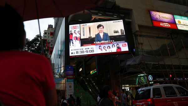 People watch a news conference of Hong Kong's Chief Executive Carrie Lam televised on a big screen in a shopping mall in Hong Kong - Sputnik International