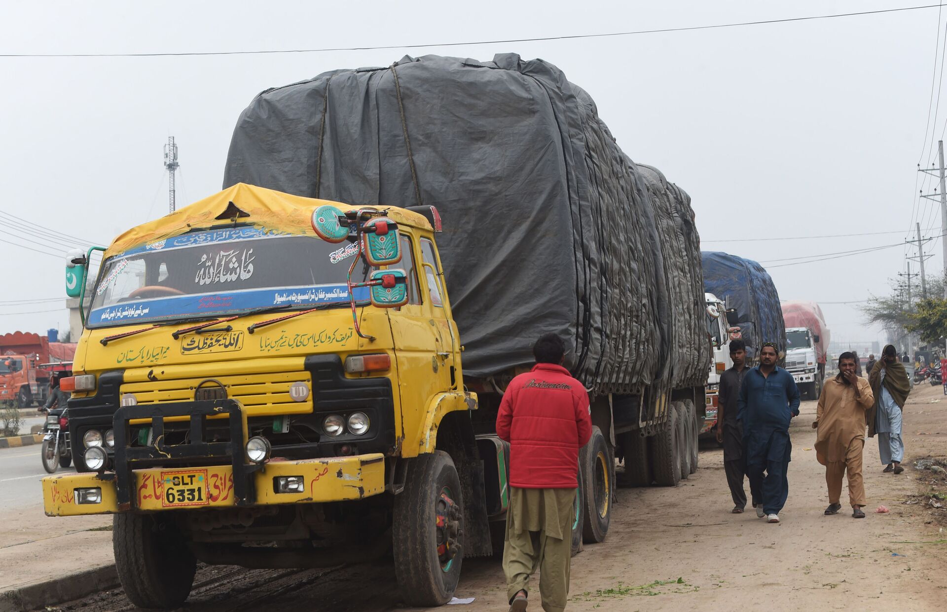 Pakistani drivers walk next to loaded trucks parked along a road near the Wagah border between Pakistan and India on February 20, 2019, following the withdrawal of trade privileges for Pakistan by the Indian government - Sputnik International, 1920, 07.09.2021